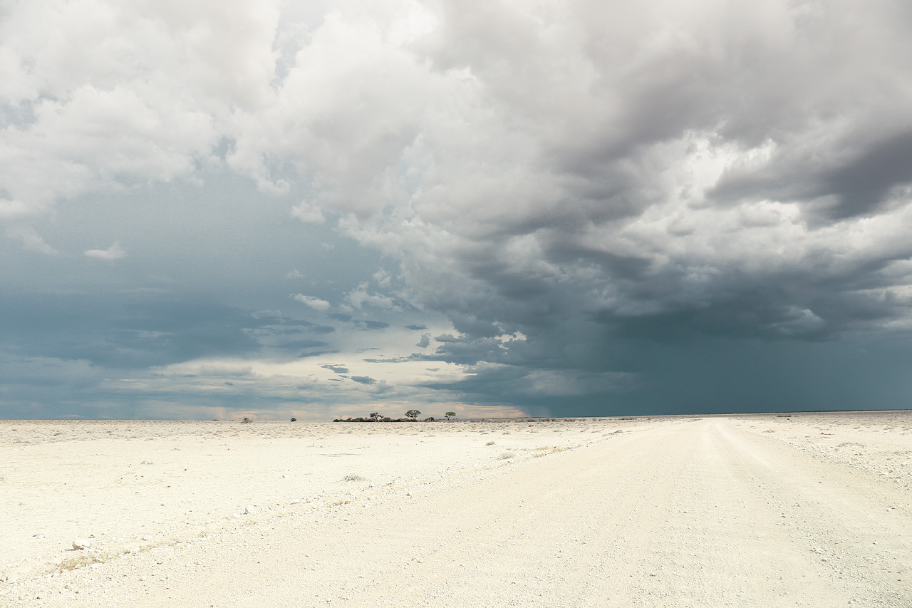 Ominous Etosha Sky Foto von Vast white Etosha Pan with dramatic storm clouds looming overhead, a quintessential Namibian vista.