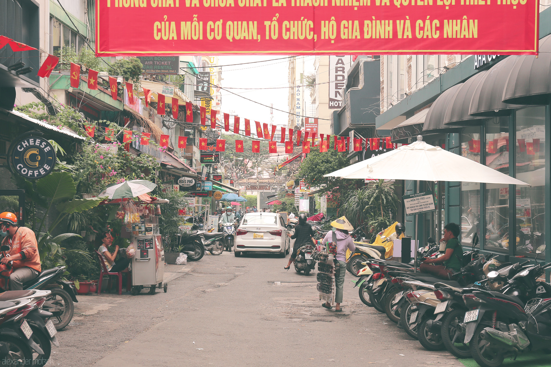 Saigon Red Ribbon Foto von A bustling alley in Saigon alive with flags, scooters, street vendors, and daily city pulse in the heart of Ho Chi Minh City, Vietnam.