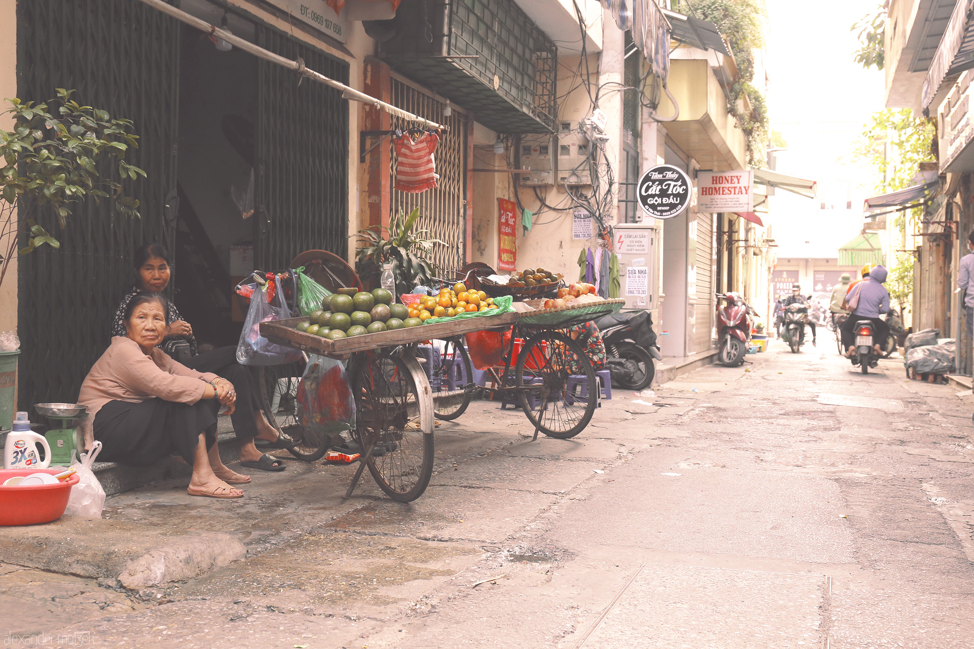 Sáng Pho Co Foto von A quiet street scene in Phuong Cua Dông, Hanoi—fruit vendors, scooters, and morning life glow in soft sunlight.