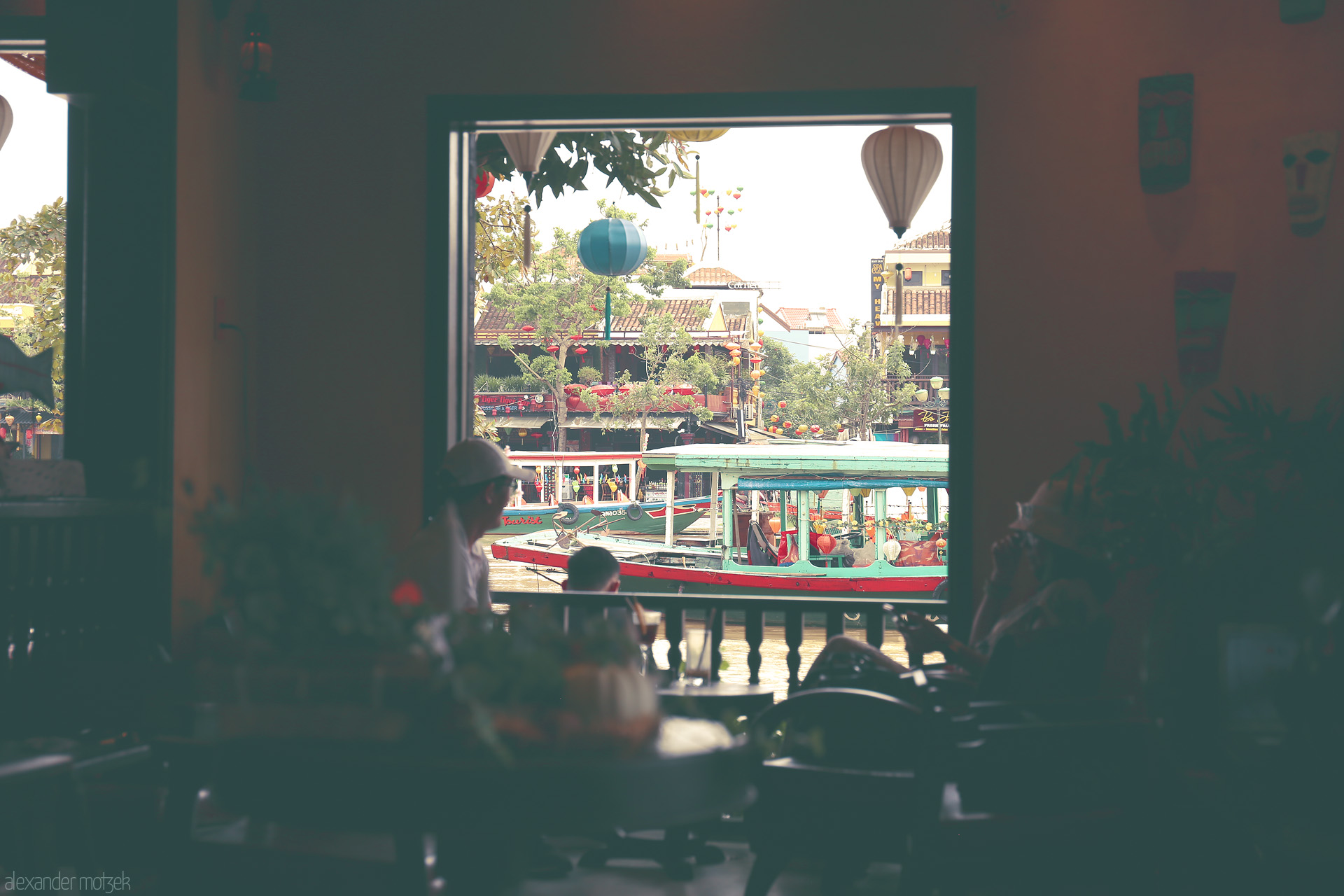 Serenade from the Shophouse Foto von A tranquil café window overlooks Hoi An's old town, colorful boats, and floating lanterns on the Thu Bon River.