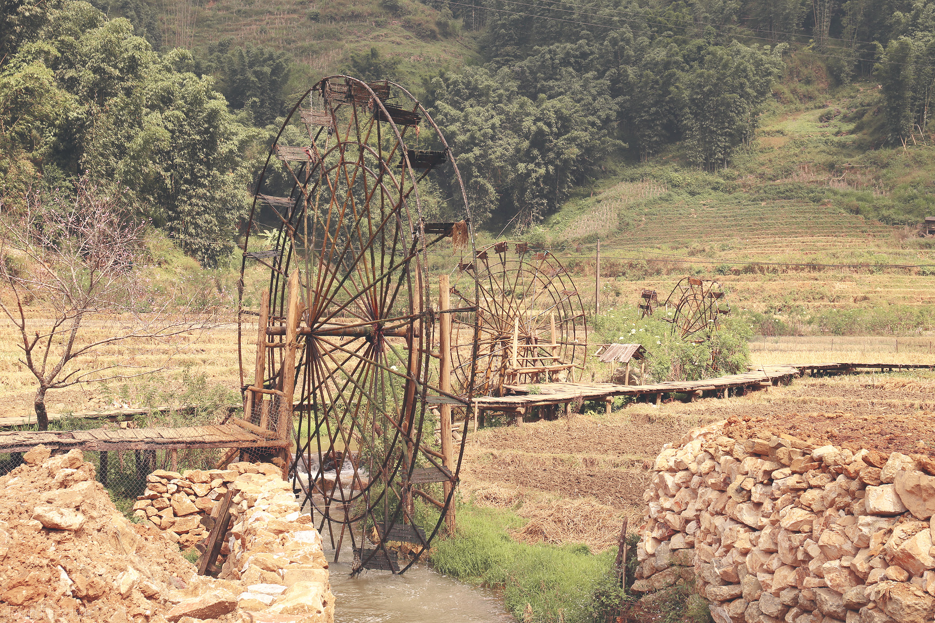 Wheels of Sapa Foto von Bamboo water wheels turn gently in Sapa’s terraced fields, blending tradition with the serene beauty of northern Vietnam’s landscape.