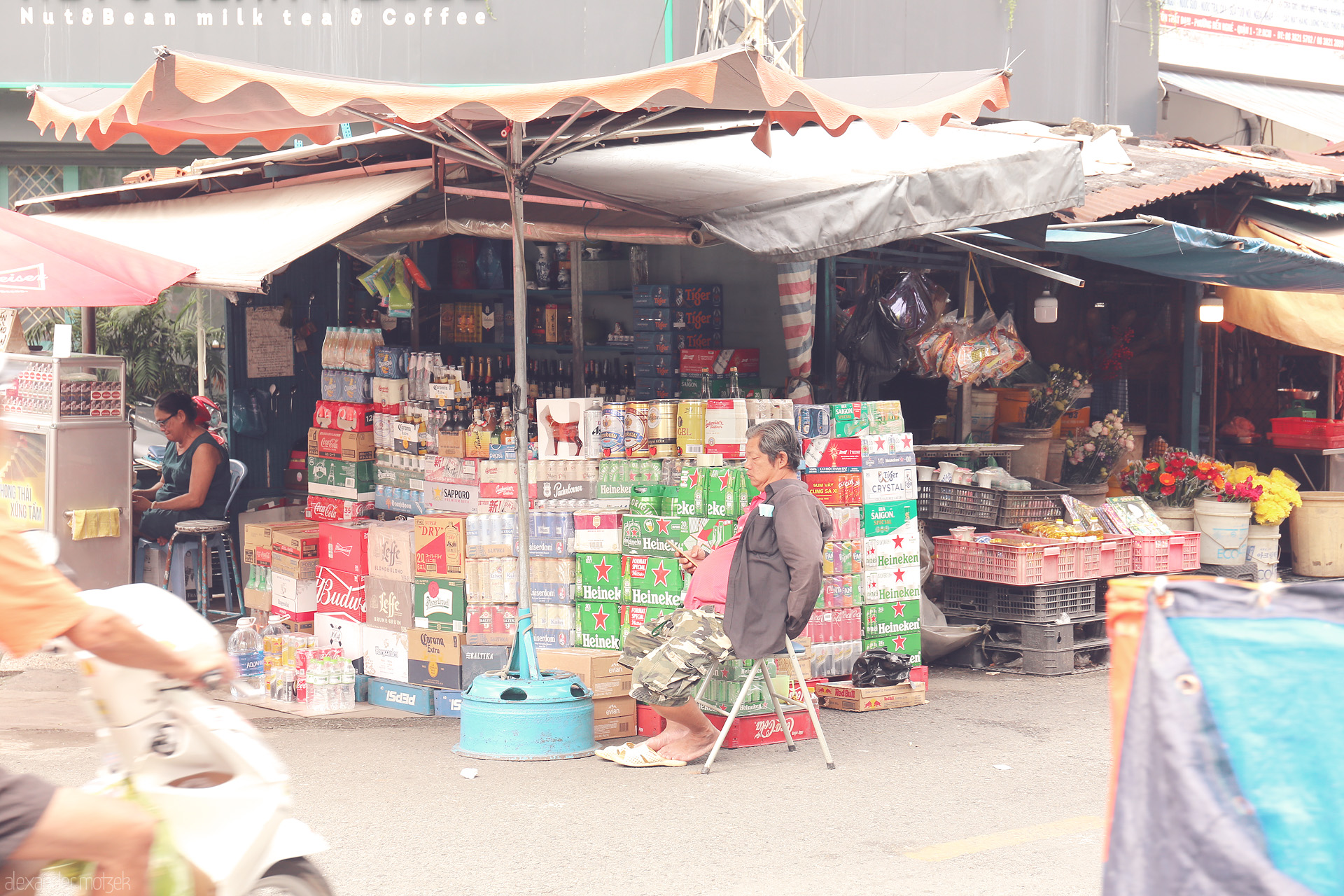 Sáng Saigon Streets Foto von Breezy street market in Ho Chi Minh City, beer crates stacked, vendors resting, and motorbikes rushing past blooms and daily life.