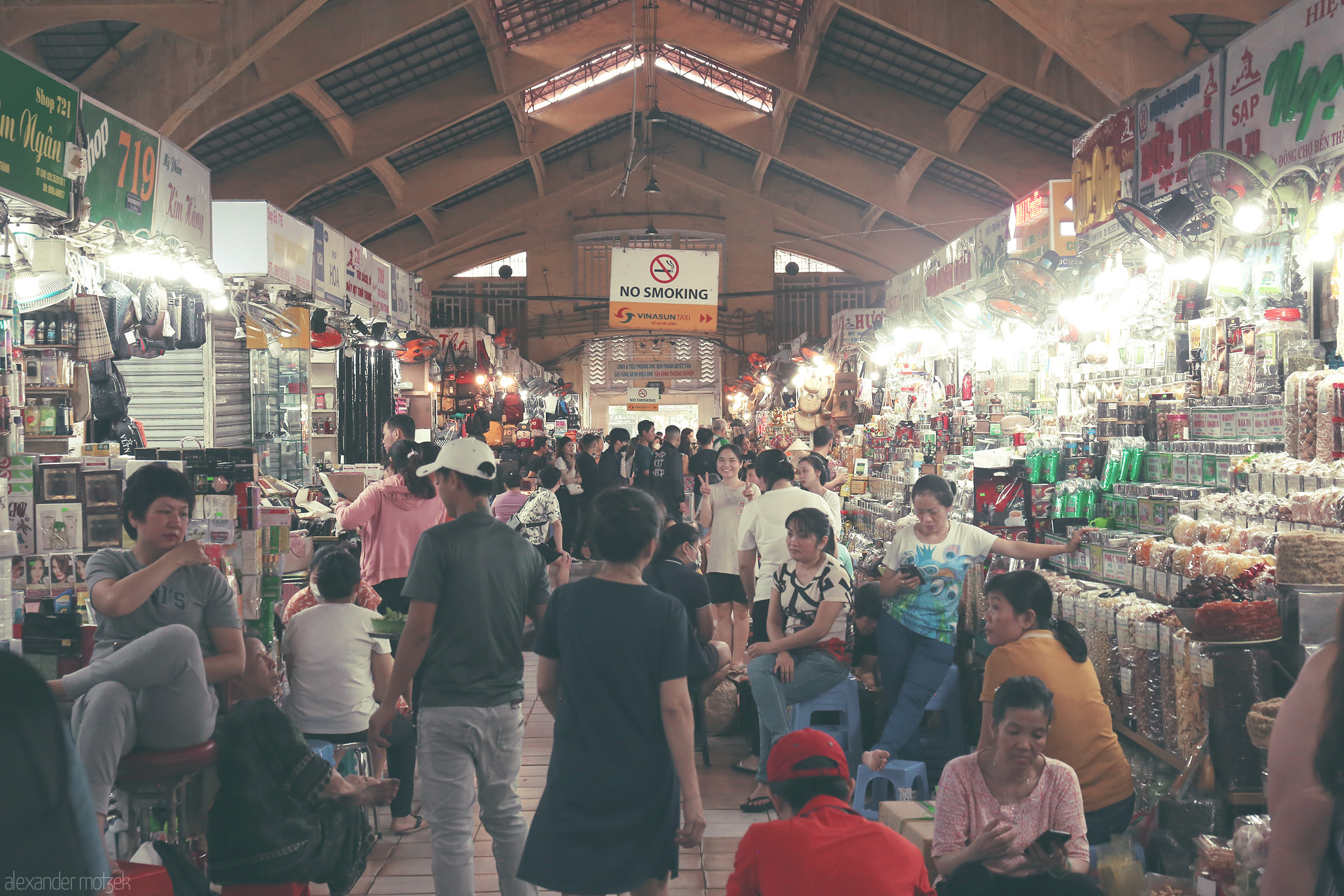 Saigon Bazaar Symphony Foto von Bustling life in Ben Thành Market, Ho Chi Minh City — locals and traders merge in vibrant chaos, under warm lights and soaring arches.