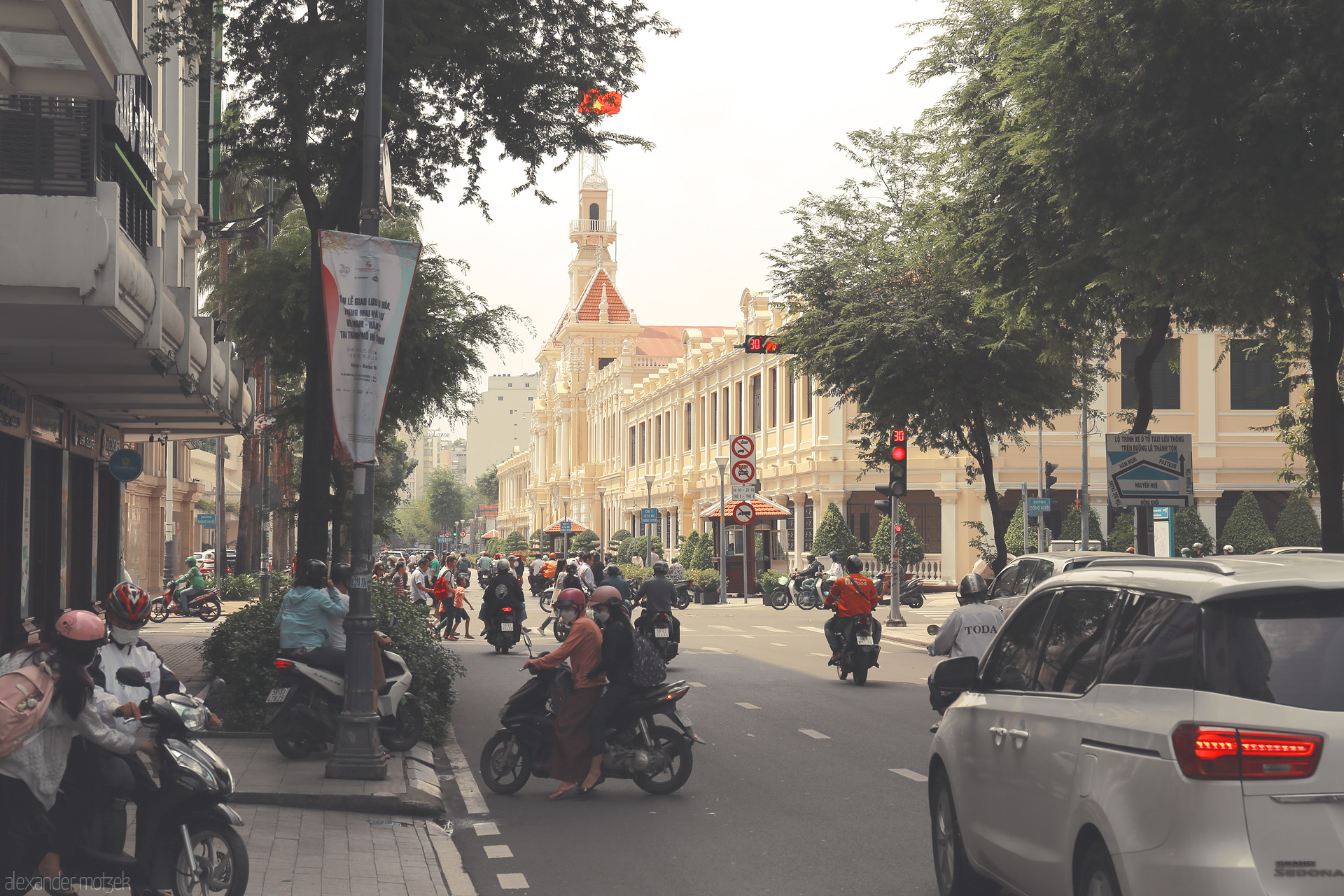 Saigon Sáng Tao Foto von Bustling motorbikes and colonial charm: a sunlit street scene at Ho Chi Minh City Hall, Saigon's beating heart.