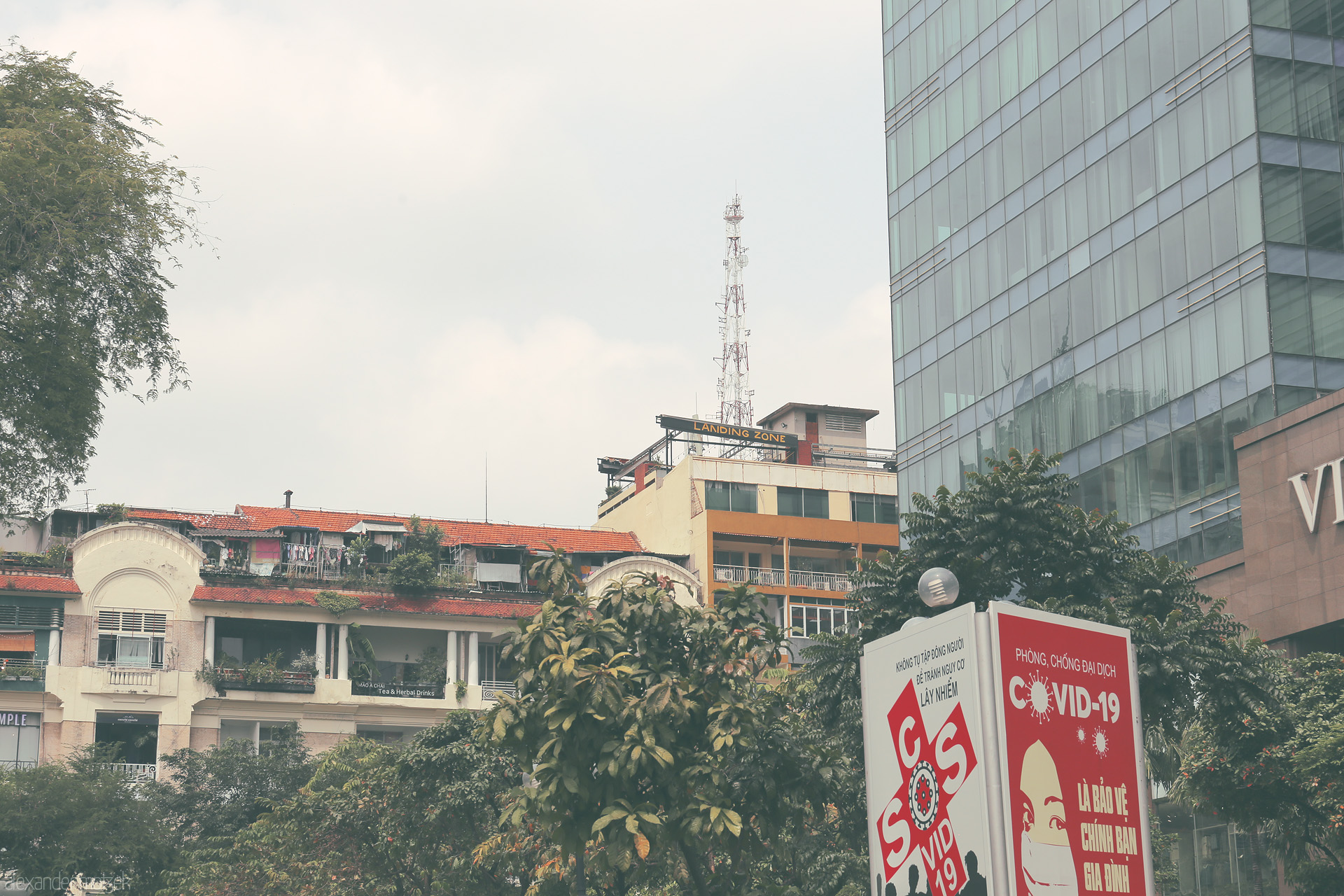 Landing Zone Layers Foto von Contrasting modern glass and vintage rooftops, COVID-19 signs stand tall in Saigon’s skyline—Ho Chi Minh City in a new era.