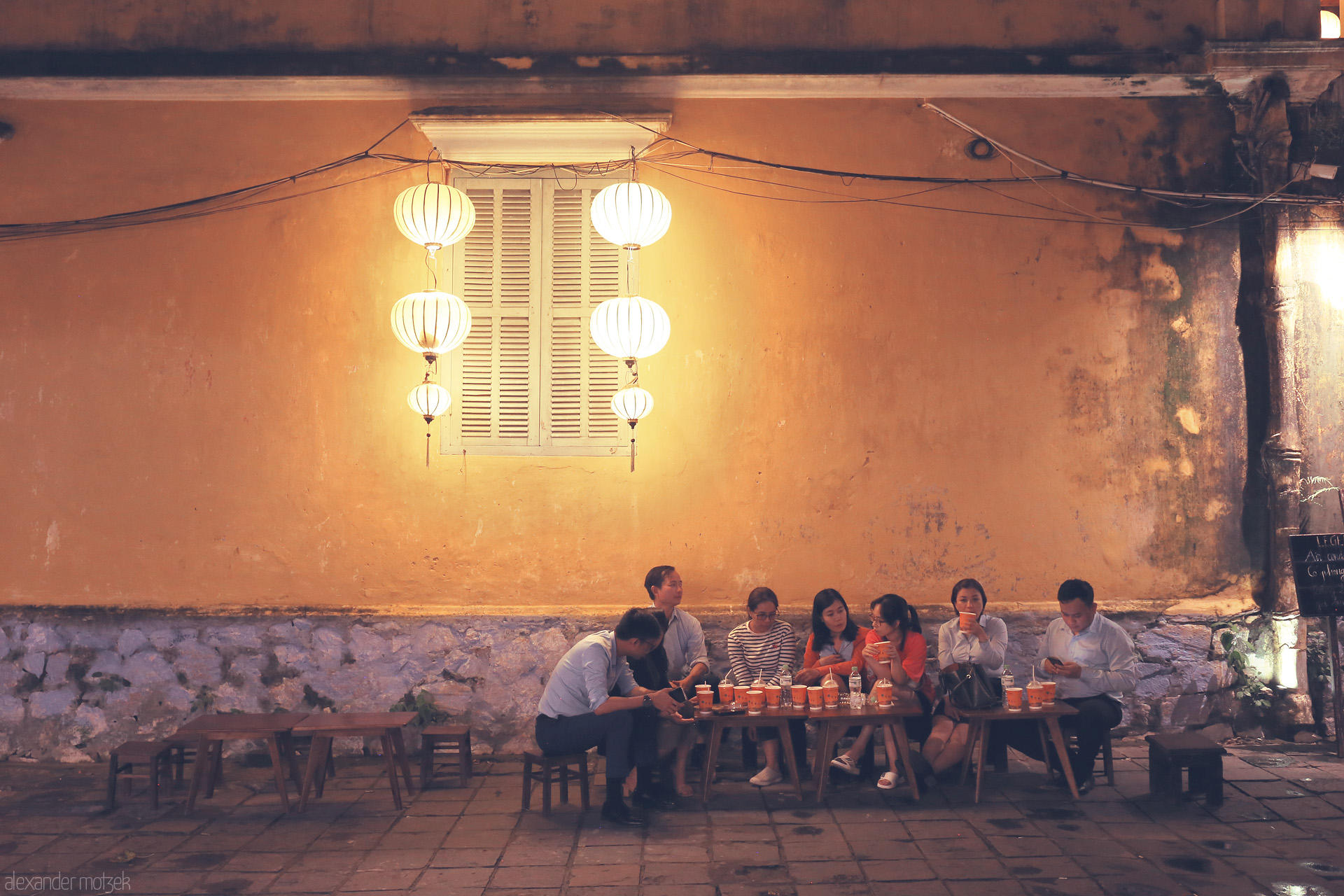 Lantern Lời Hoi An Foto von Locals savor street food under glowing lanterns, old town vibes radiating from a golden wall in Hoi An, Vietnam.