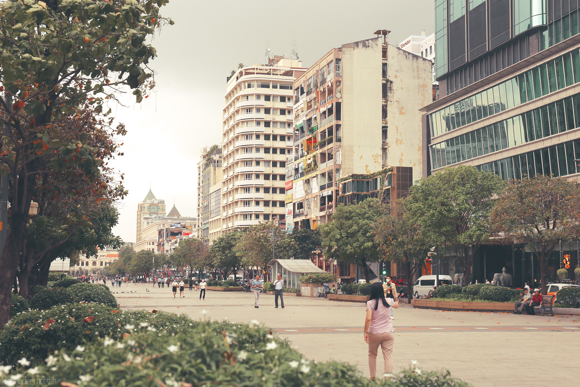 Pastel Pulse of HCMC Foto von Locals stroll Nguyen Hue walking street, framed by vintage apartments and glass towers in Ho Chi Minh City's bustling heart.