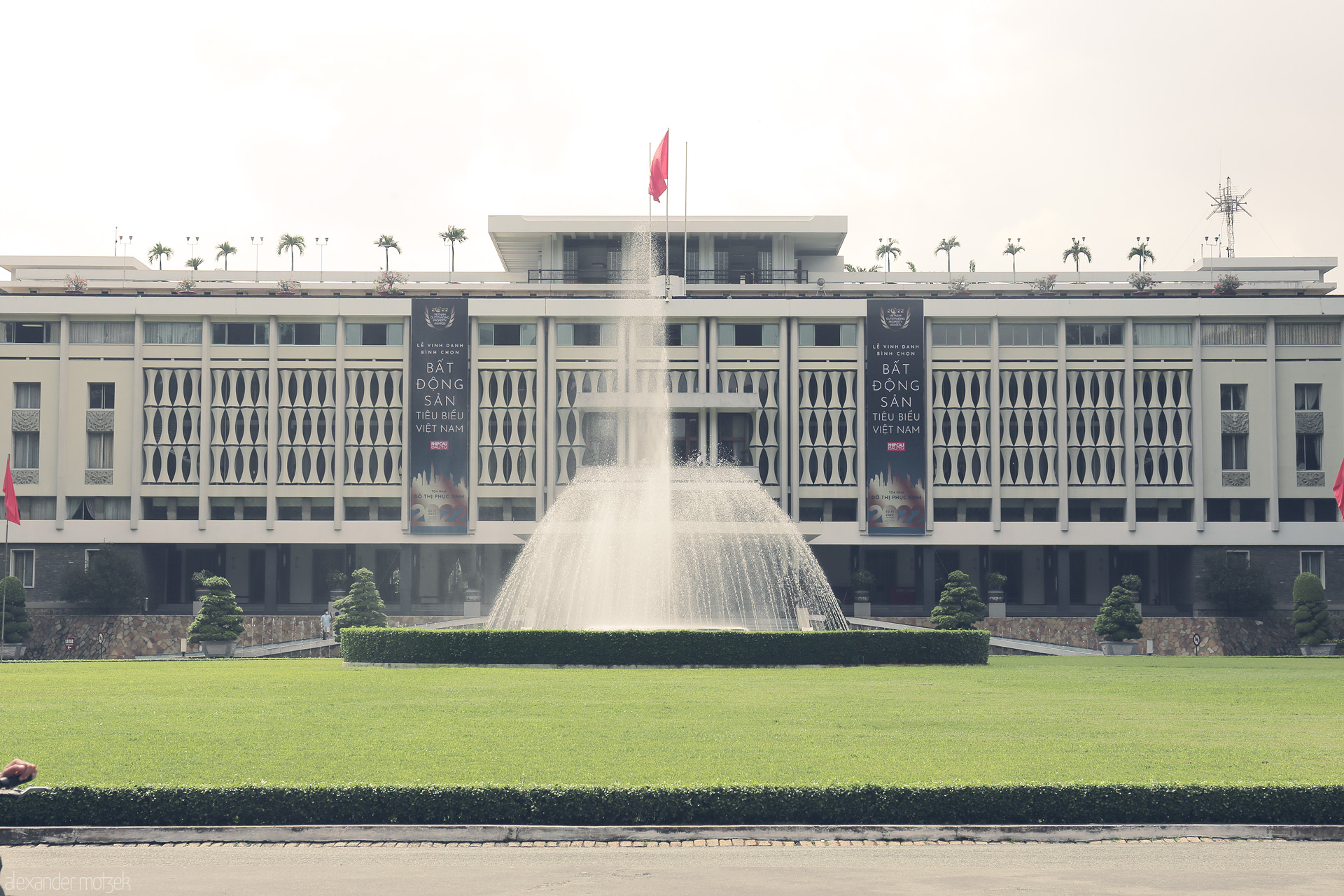 Fountain of Reunification Foto von The iconic Reunification Palace stands tall amid lush Saigon gardens, its fountain glittering in Vietnam’s midday sun.
