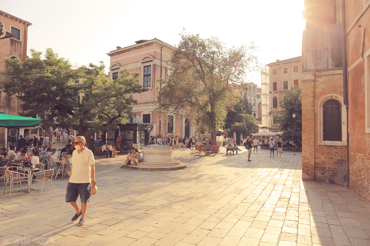 Luci di Venezia Foto von Warm sunlight bathes a bustling Venetian piazza, capturing the essence of daily life in the iconic city.